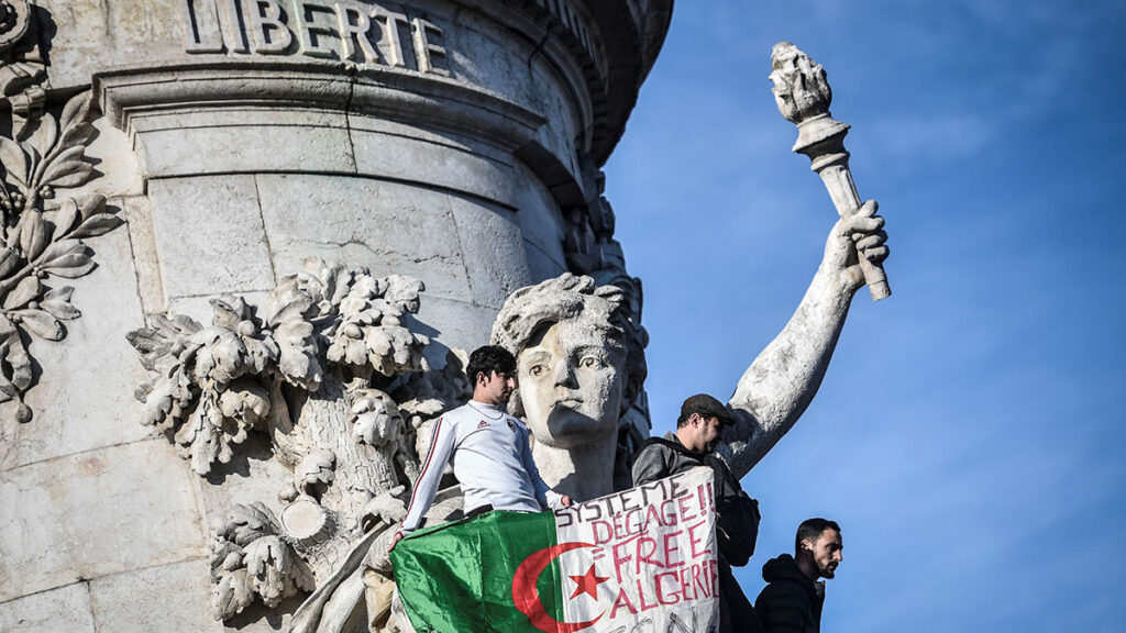 FRANCE-ALGERIA-POLITICS-VOTE-DEMO The Algerian flag with the words written on it that read, 'System get out, free Algeria' is held as protesters rally against the Algerian president's bid for a fifth term in office on February 24, 2019 at the Place de la Republique in Paris. - President Abdelaziz Bouteflika is Algeria's longest-serving president and a veteran of its independence struggle who has clung to power since 1999 despite his ill health. (Photo by STEPHANE DE SAKUTIN / AFP) (Photo credit should read STEPHANE DE SAKUTIN/AFP/Getty Images)